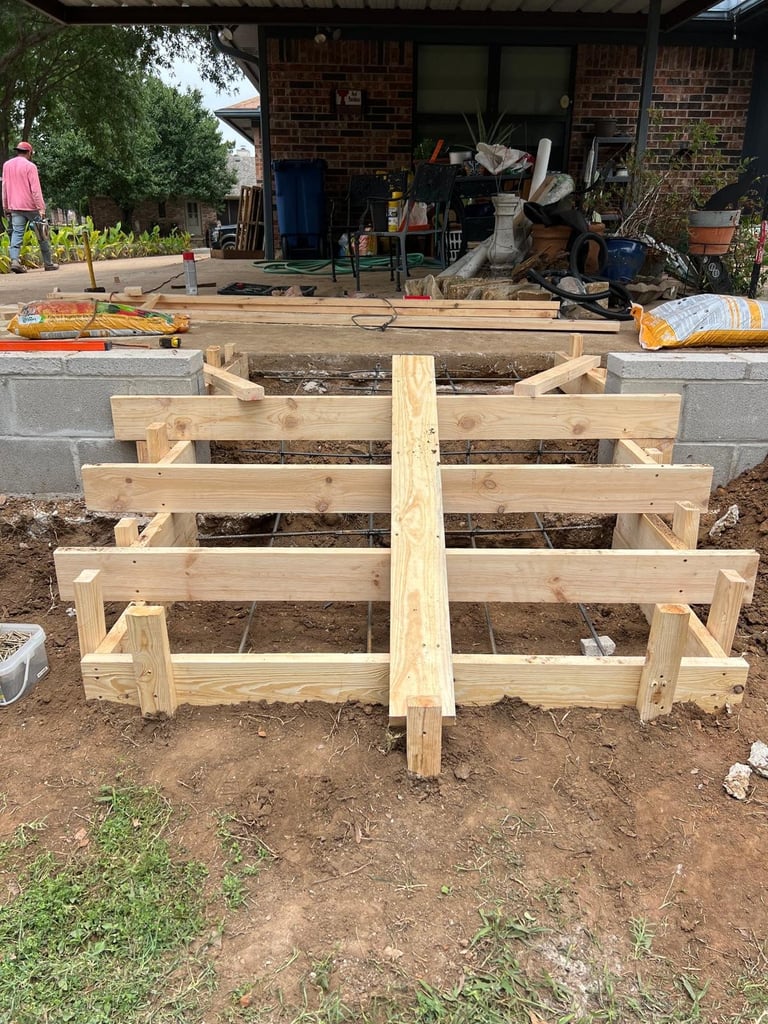 Wooden deck or porch frame under construction in a backyard with brick house and landscaping visible in background