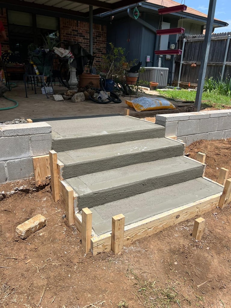 Concrete outdoor steps with wooden side railings under construction in a residential backyard