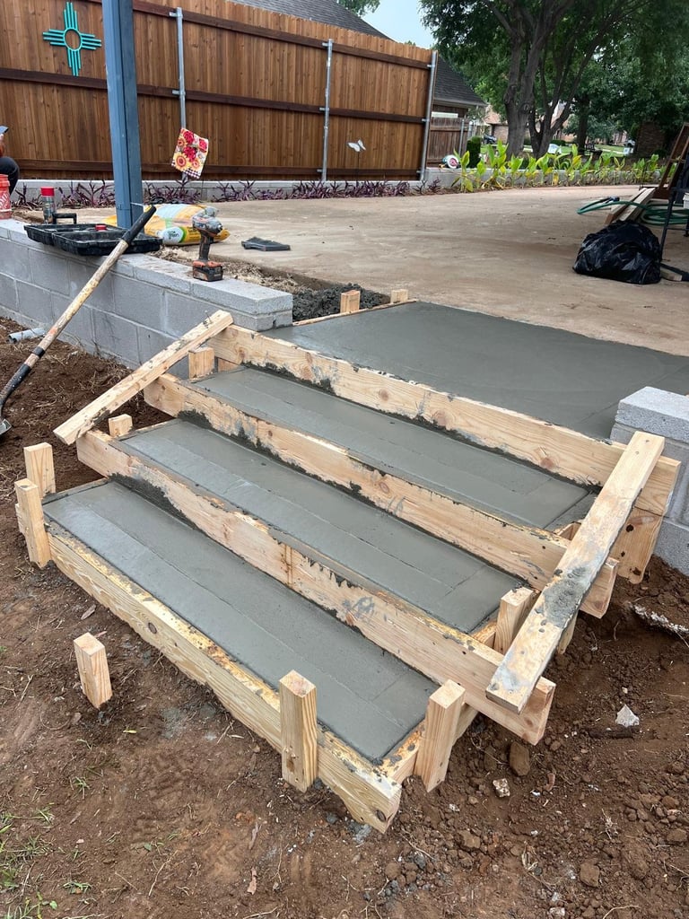 Wooden raised garden beds with gray soil under construction on a paved outdoor work area