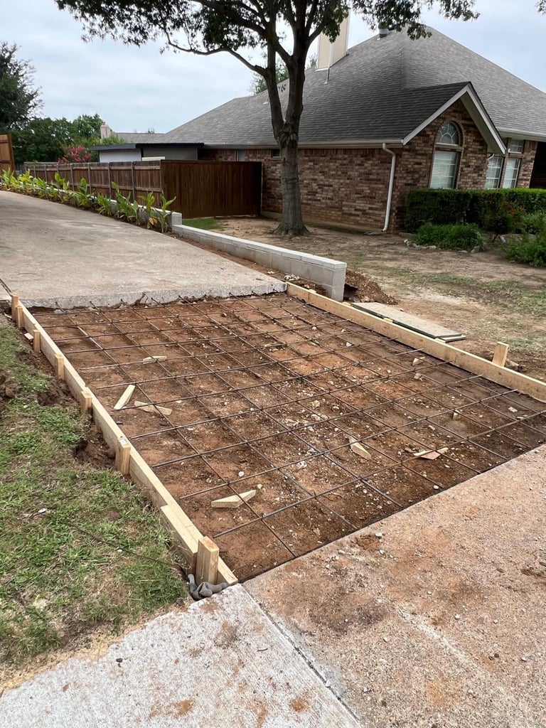 Wooden framed garden bed construction in front yard of brick house with mature tree and driveway